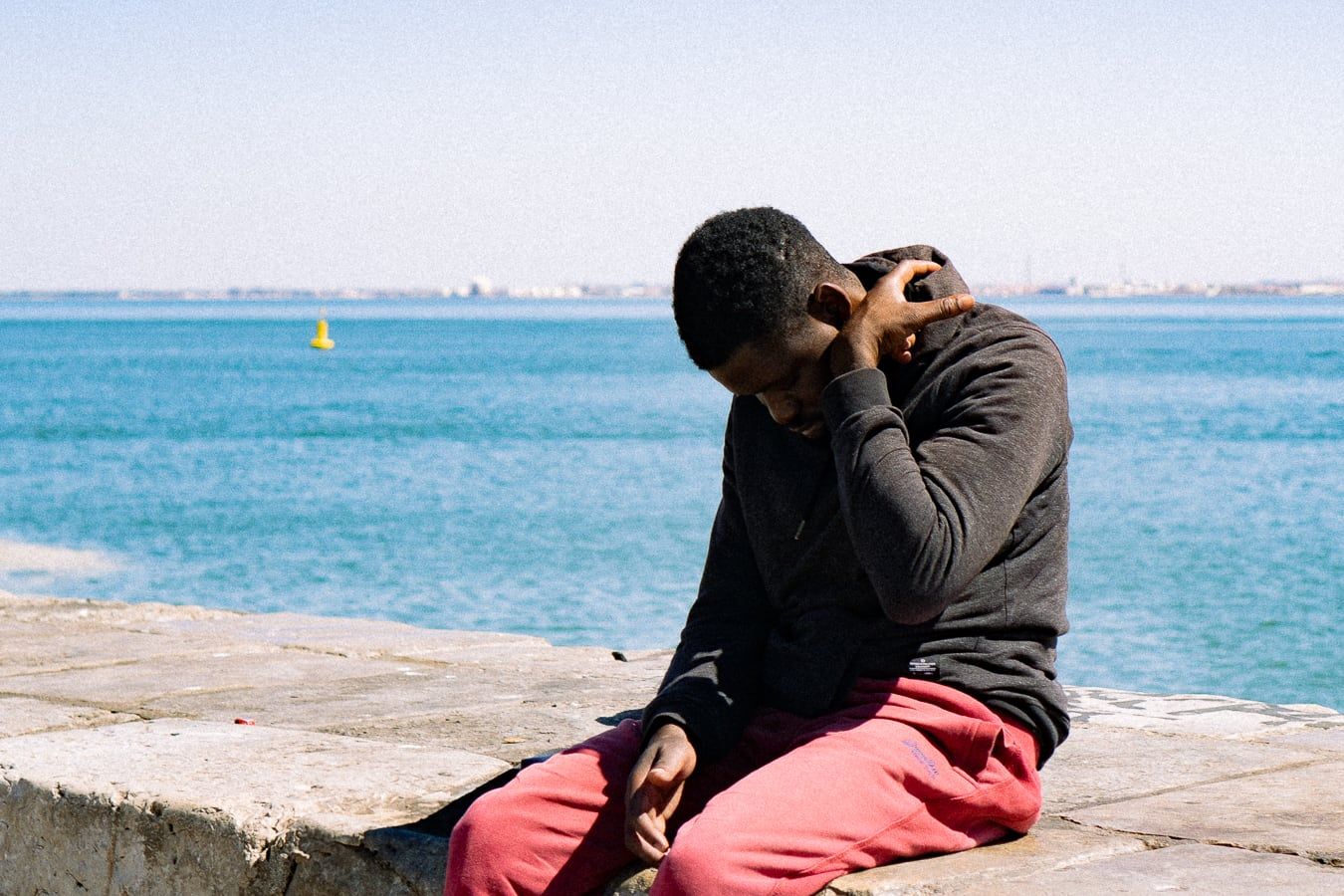 A man in red trousers by the sea